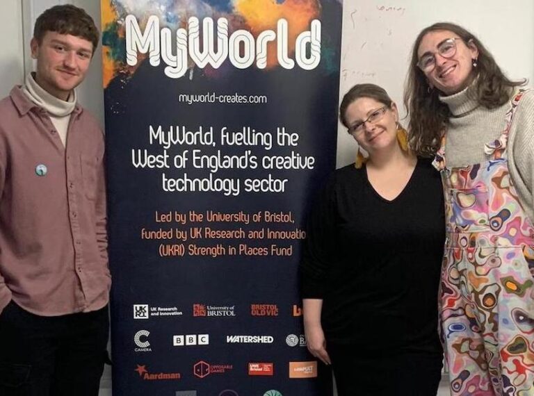 Three people standing by a MyWorld banner