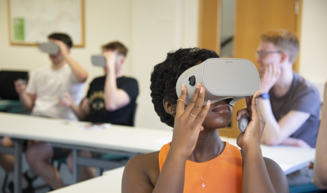 A woman wearing a VR headset wearing an orange vest looking upwards