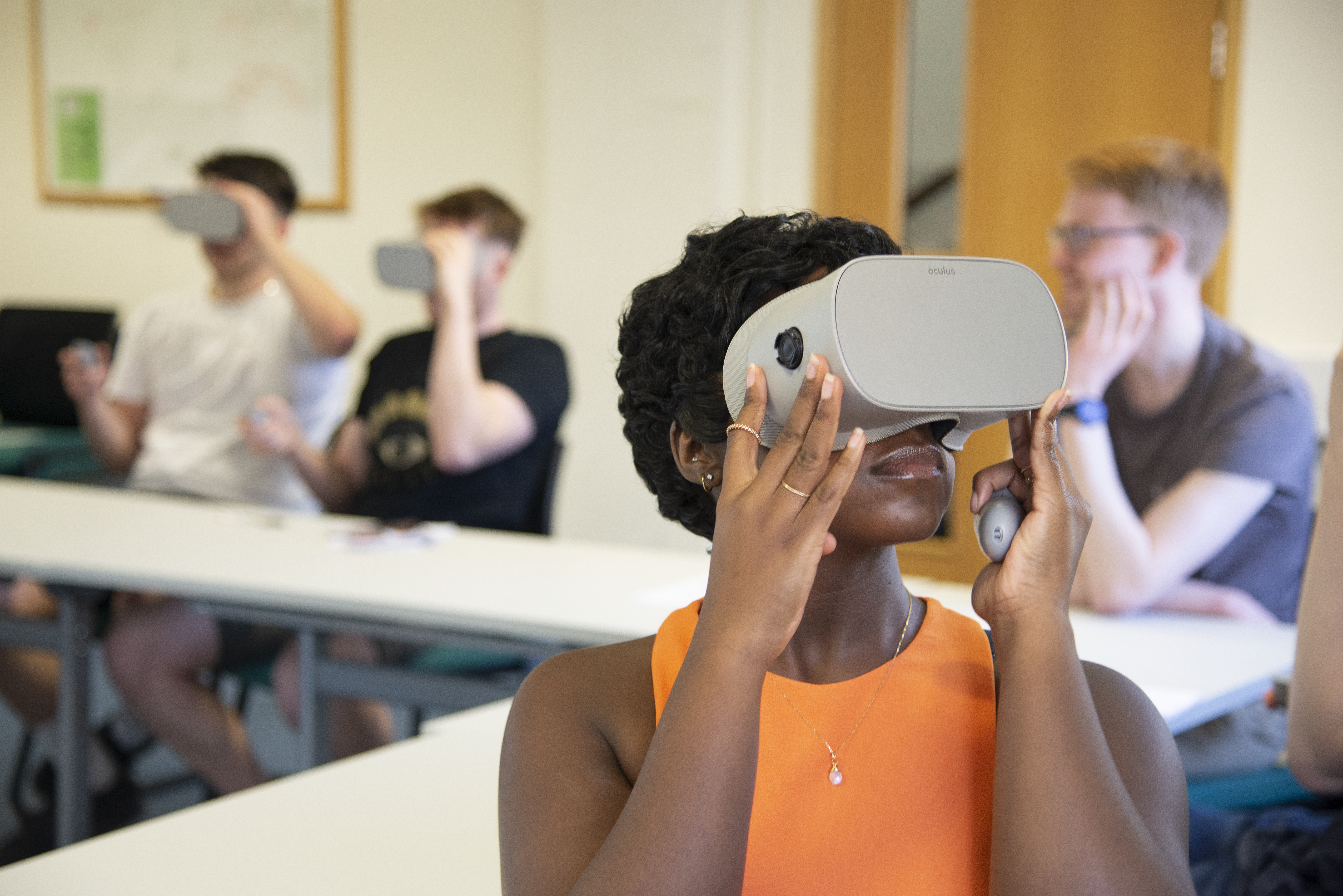 A woman wearing a VR headset wearing an orange vest looking upwards