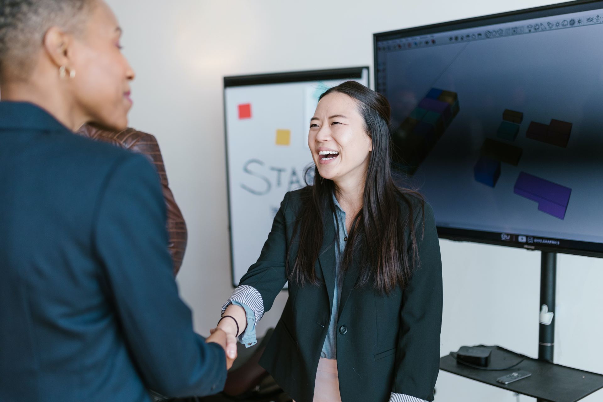 An image of two women shaking hands smiling.