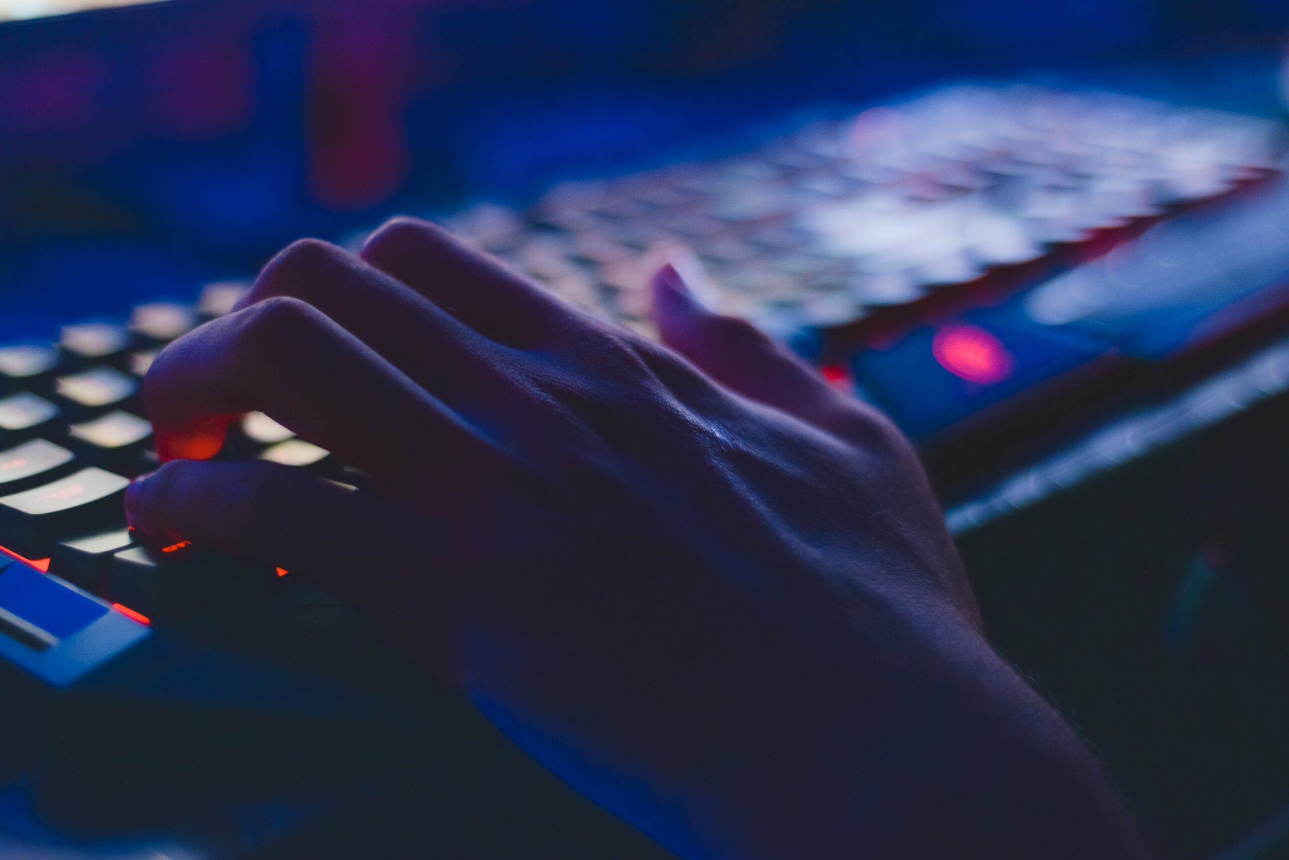 A hand hovering over a lit up keyboard