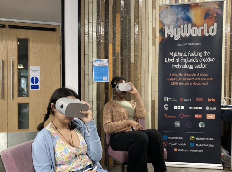 2 girls wearing a vr headset in front of MyWorld banner