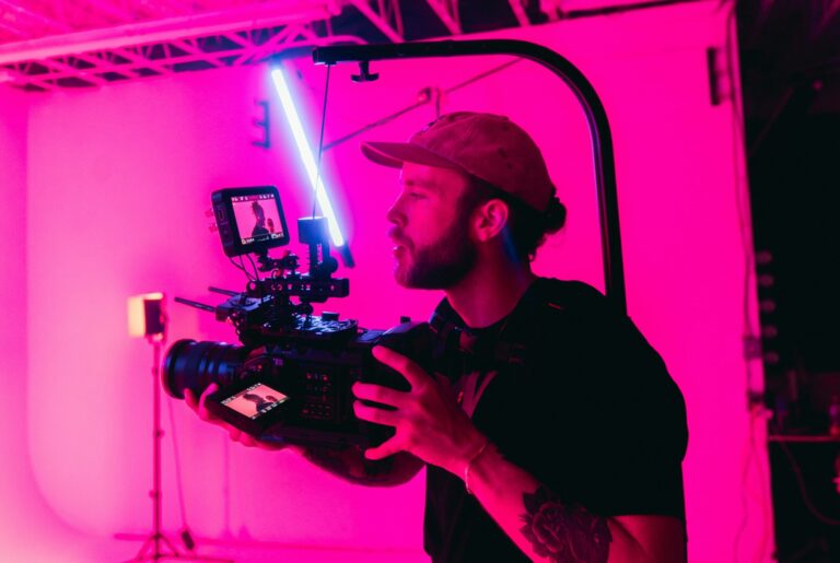 a man with a camera against pink background