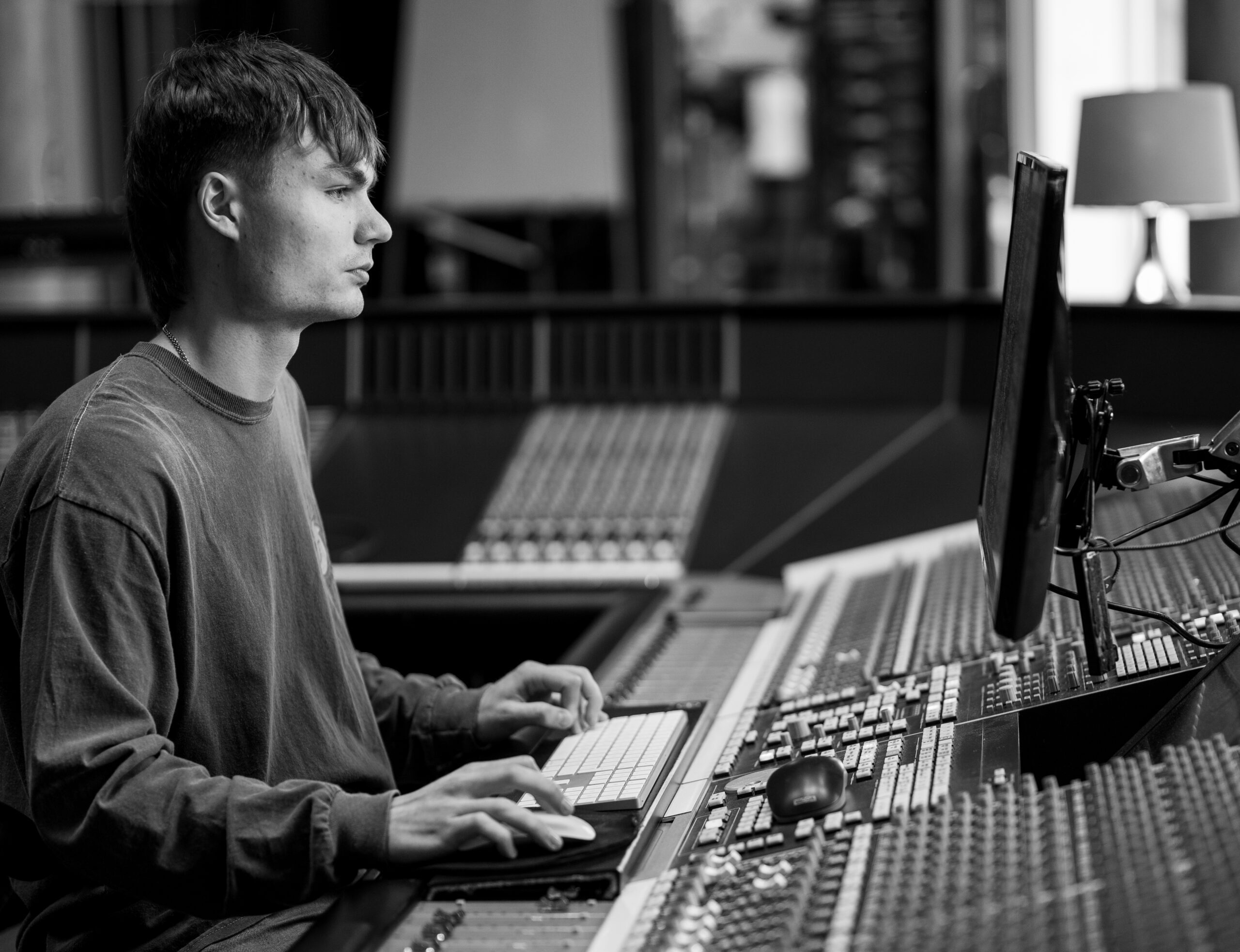 A black and white image of a man at a music mixing studio.
